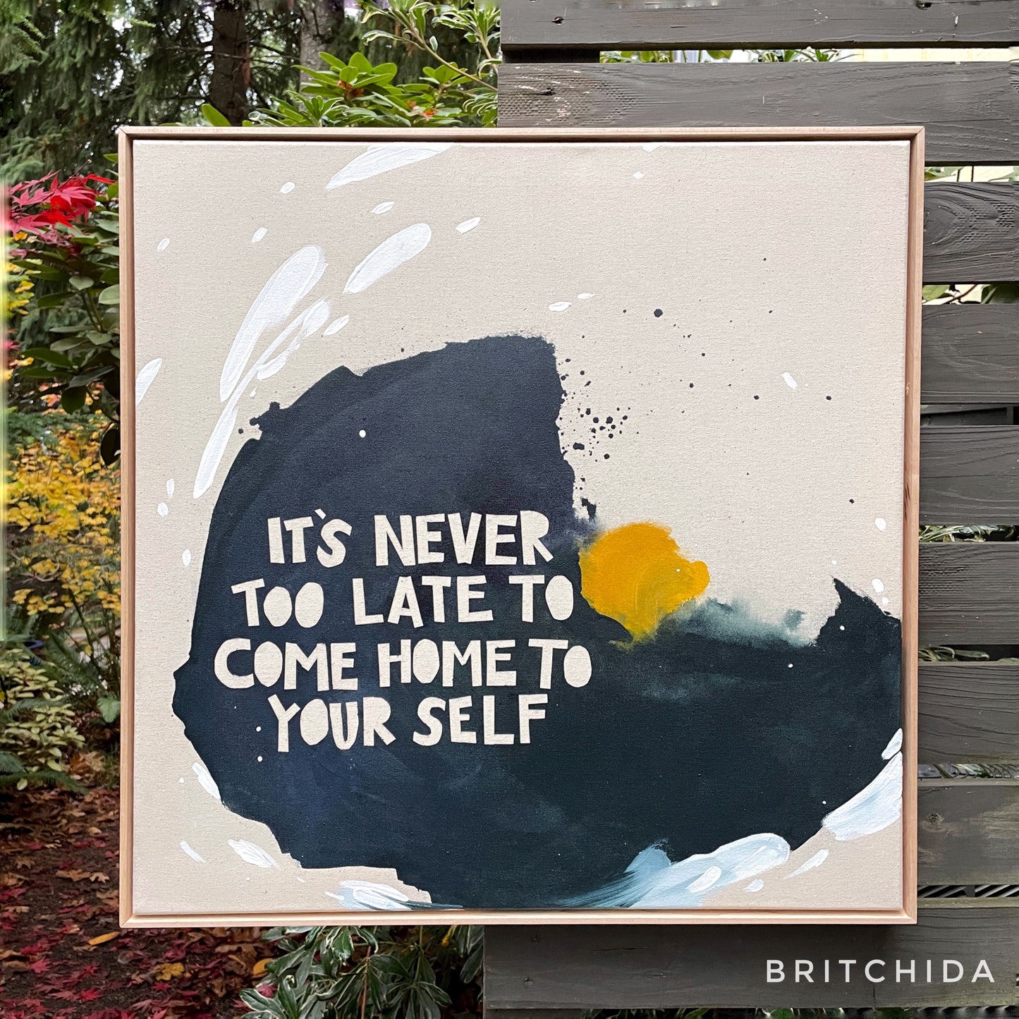 Framed print of canvas artwork by artist britchida with blue, yellow, and white colors. There is text n relief of the blue paint that reads, "It's never too late to come home to yourself."