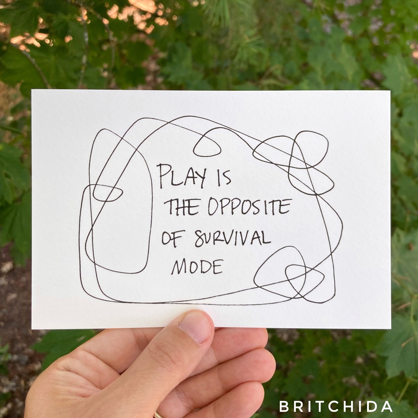 a 4 inch by 6 inch art print that says “play is the opposite of survival mode” with line art around it.