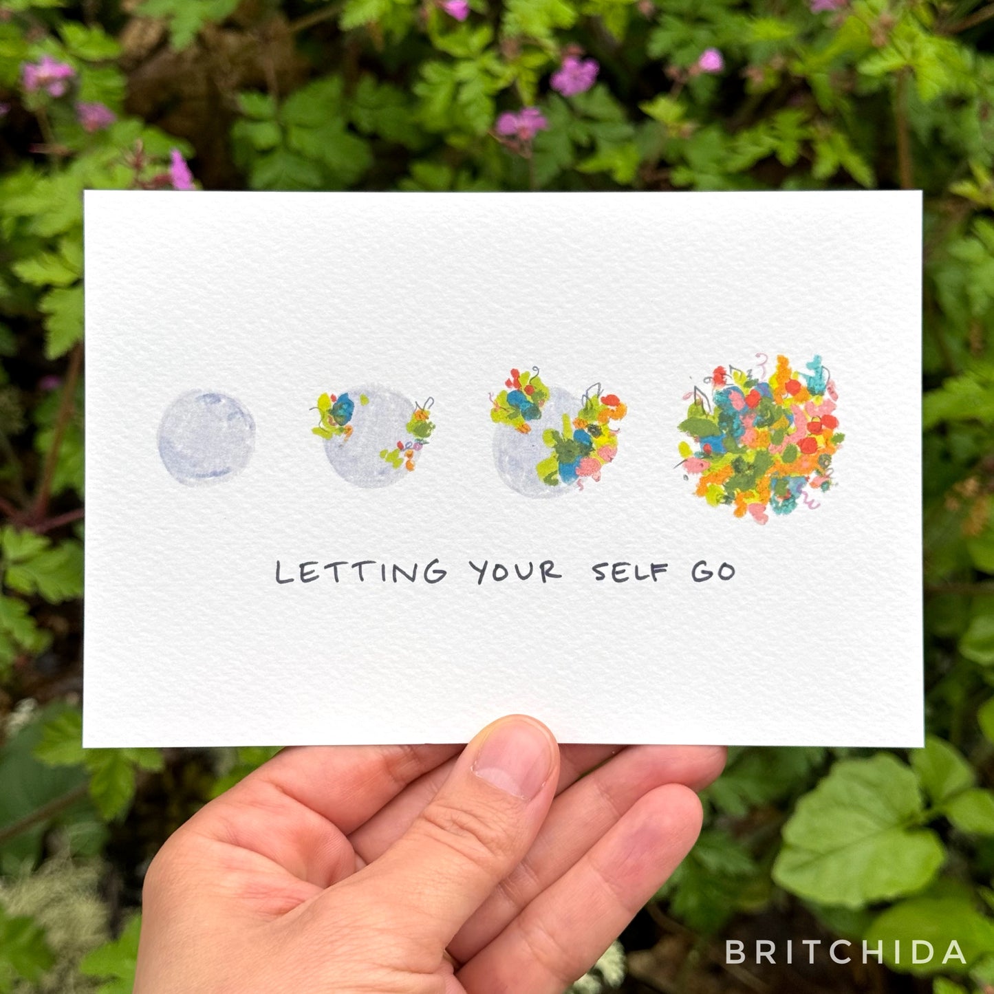 a series of four gray globes — the first one bare, the next ones each with increasing amounts of abstract color marks on them in a floral motif until the last one which is fully covered. Below is the text, “letting yourself go”
