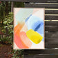 abstract painting by Britchida hanging on a wooden fence with various shapes of yellow, blue, ice blue, pink, orange, and white