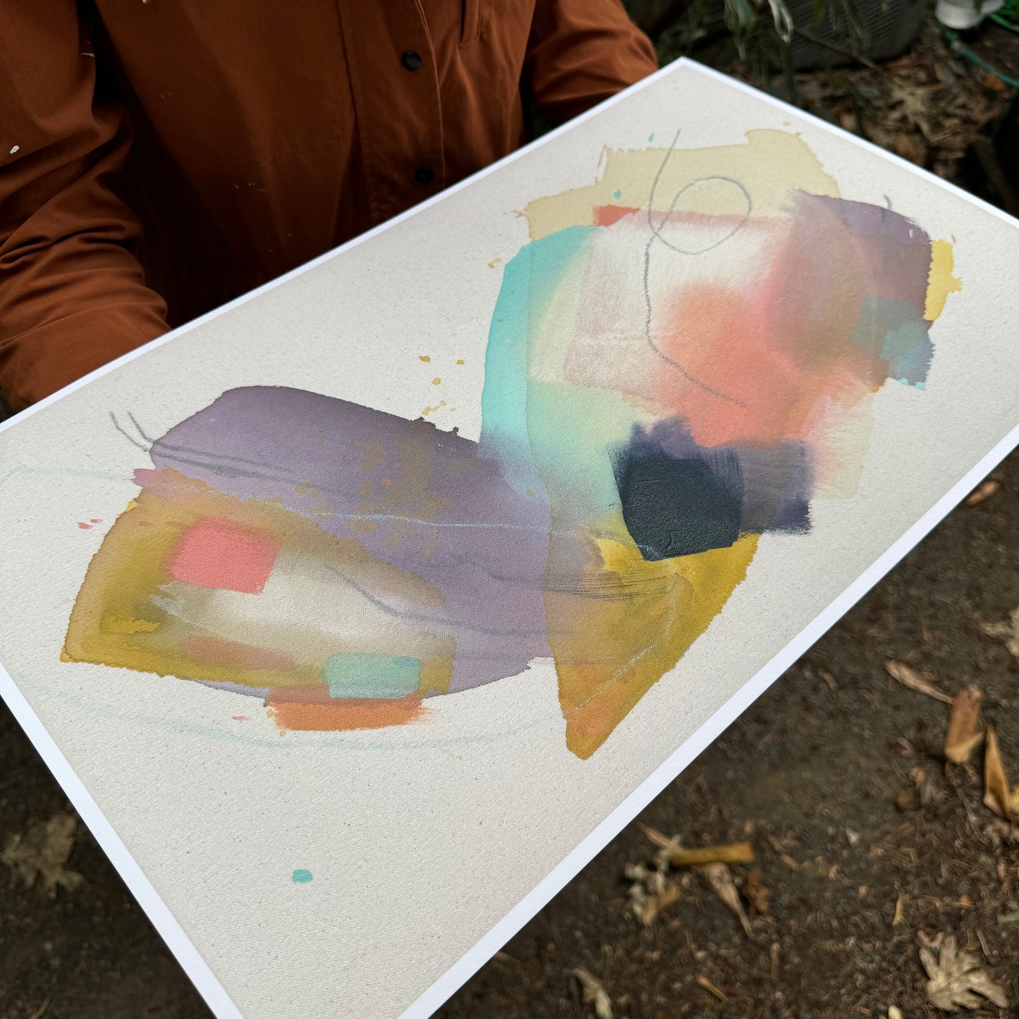 person in orange jacket holding a  print of abstract painting by britchida with yellow, teal, peach, navy, and lilac shapes with various thin lines