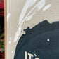 close up photo of original painting by britchida showing tan canvas with white and navy shapes 