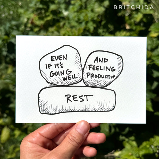 two large rocks sit on an even larger one. The bottom one says “rest” and the top two say “even if it’s going well” and "and feeling productive.”