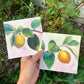 print set of 2 gouache paintings of lemons hanging from a branch with a pink background