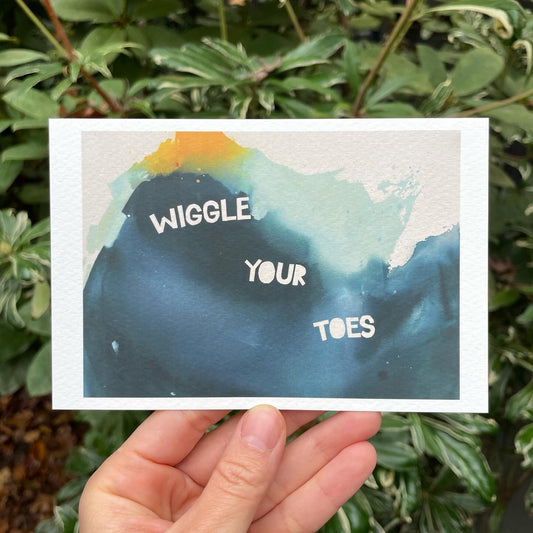 4x6" print of abstract painting by britchida. blue, teal, and yellow shapes on white background. white block text steps down and says "WIGGLE YOUR TOES"