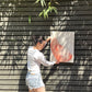 photo of person with dark hair, white long-sleeved shirt, and jean shorts holding original abstract painting by britchida with pink and white shapes and lines on canvas.