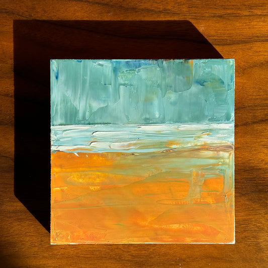 small landscape painting on wood of beach with sand in the foreground and small waves and blue sky