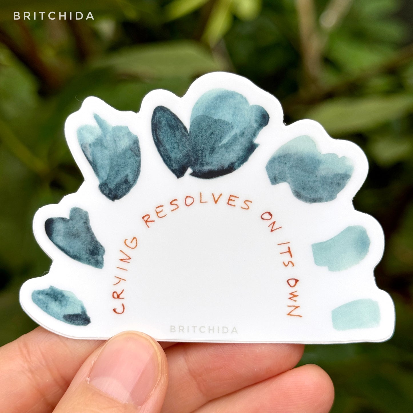 sticker with an arch of blue watercolor dots that become lighter blue towards the right. Below is an arch of text reading "crying resolves on its own"