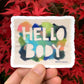 sticker of Hello Body print with cutout block letters "HELLO BODY" and various colors of paint on a canvas with ripped edges. 