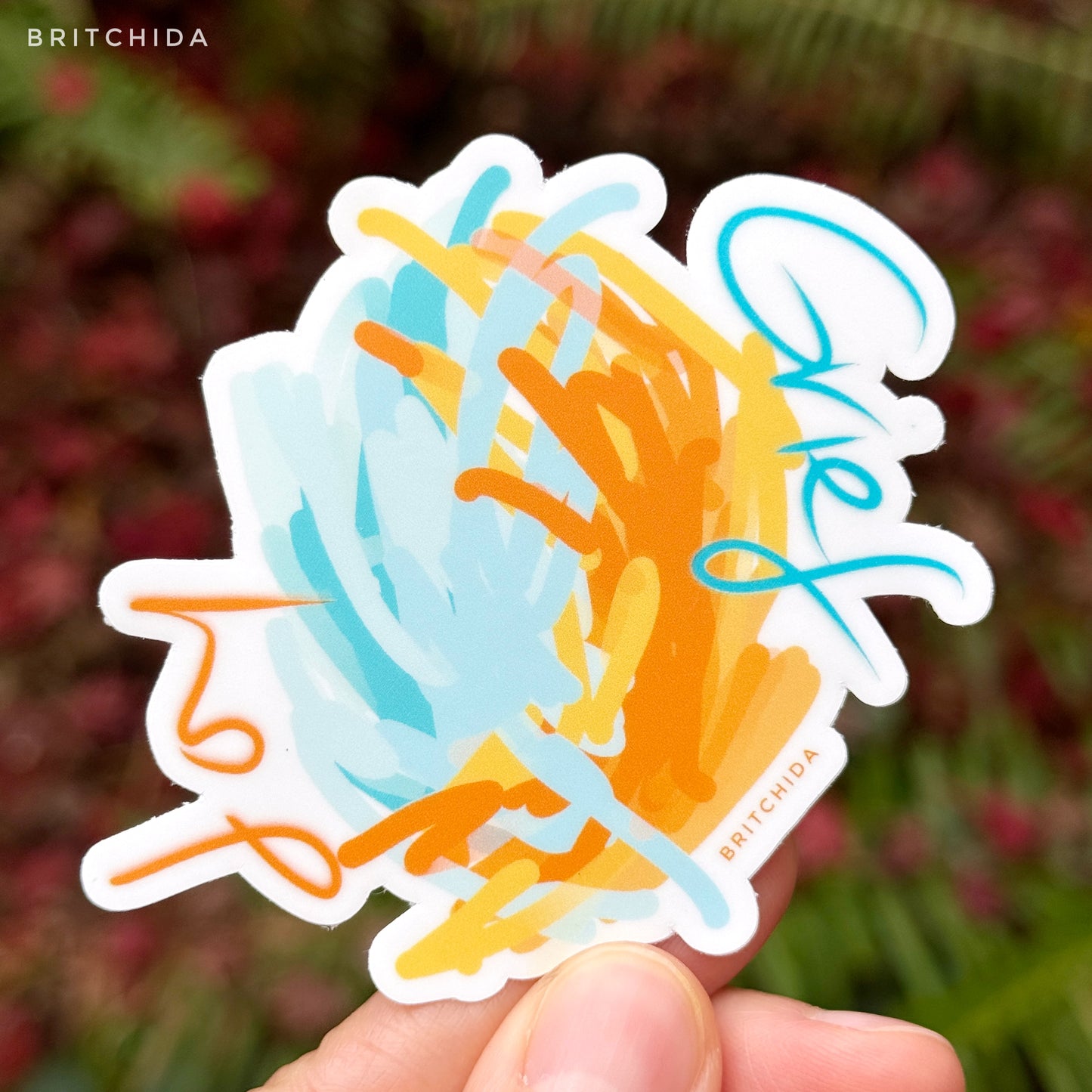 sticker of Joy/Grief print with orange and blue interlocking paint strokes with the words "joy" and "grief" on opposite sides