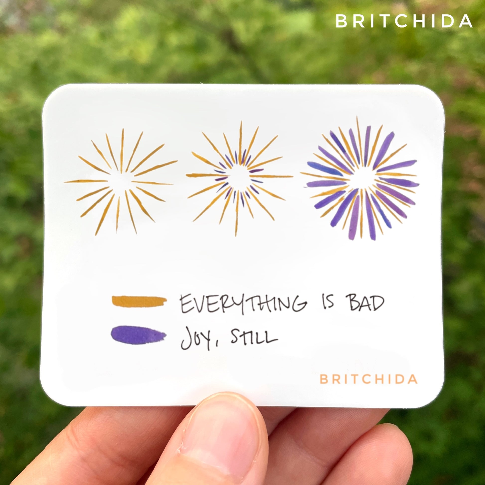 sticker of Joy, Still print with 3 radiating star shapes. The first one on the left is mostly yellow lines. The second one is yellow with short purple lines. The third one on the right is equal length yellow and purple lines but the purple lines are thicker. The yellow is labeled "everything is bad" and the purple is labeled "joy still"