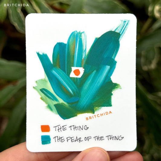 sticker of The Fear of the Thing print with abstract green and teal paint strokes with a cutout in the center holding a single orange dot. The orange is labeled "the thing" and the green is labeled "the fear of the thing"